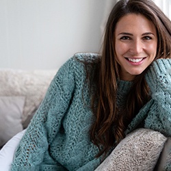 Woman sitting on couch at home and smiling