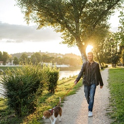 a person walking their dog on a trail and smiling