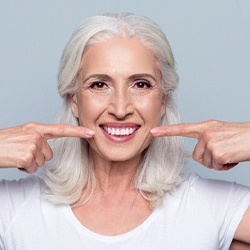 Older woman pointing to her dentures