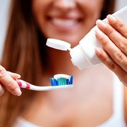 Smiling woman putting toothpaste on toothbrush