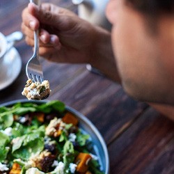 Man eating salad at table with cup of tea