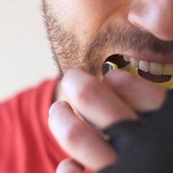 Man putting yellow and black mouthguard in mouth