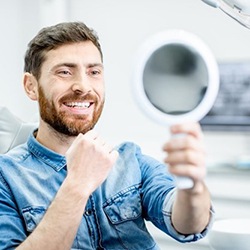 dental patient with tooth-colored fillings in Arlington admiring his smile in a mirror 