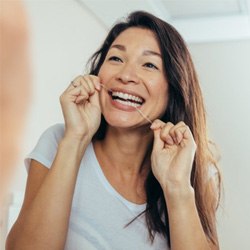 a woman flossing for dental implant care in Arlington