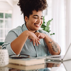 Woman smiling while working on laptop at home