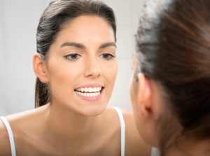Woman examining smile for signs of gum disease 