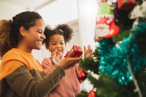 parent helping their child decorate a tree