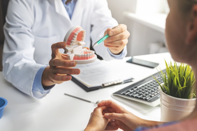 Dentist showing model of teeth to patient