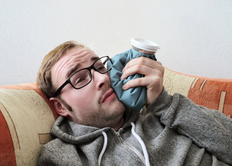 young man holding ice pack to jaw