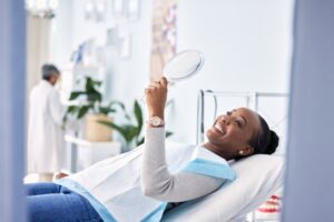 smiling woman in the dental chair looking in a mirror